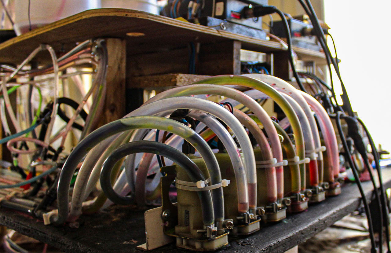 Row of solenoid valves with looping tubes, feeding fluid into the sculpture's circulation system.